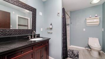 A bathroom with a dark wooden vanity, a white toilet, and a shower curtain.