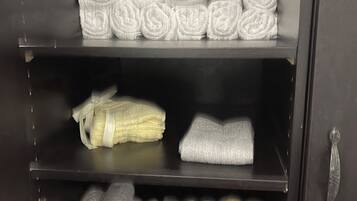 A storage cabinet with shelves holding neatly rolled towels in various colors.