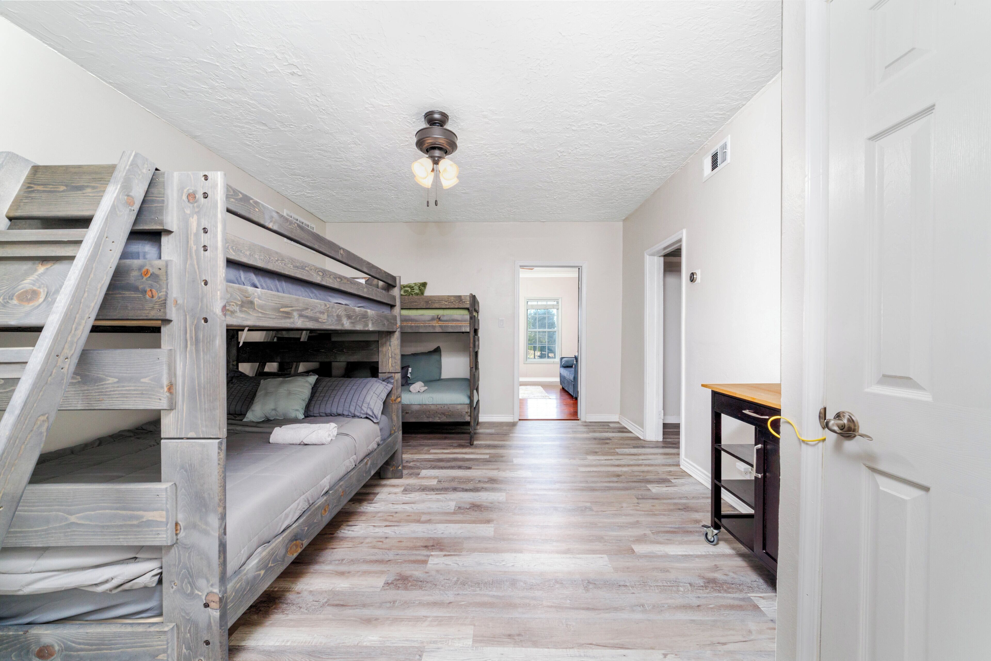 A room with bunk beds, a ceiling fan, and a wooden floor.