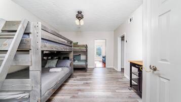 A room with bunk beds, a ceiling fan, and a wooden floor.