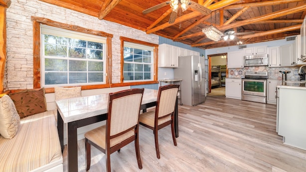 A spacious kitchen with wooden beams, a dining area with a table and chairs, and a view through large windows. - CDNH Villa at Katy Lake (Katy)