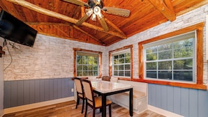 A dining area with a wooden ceiling, stone wall, and large windows. - CDNH Villa at Katy Lake (Katy)