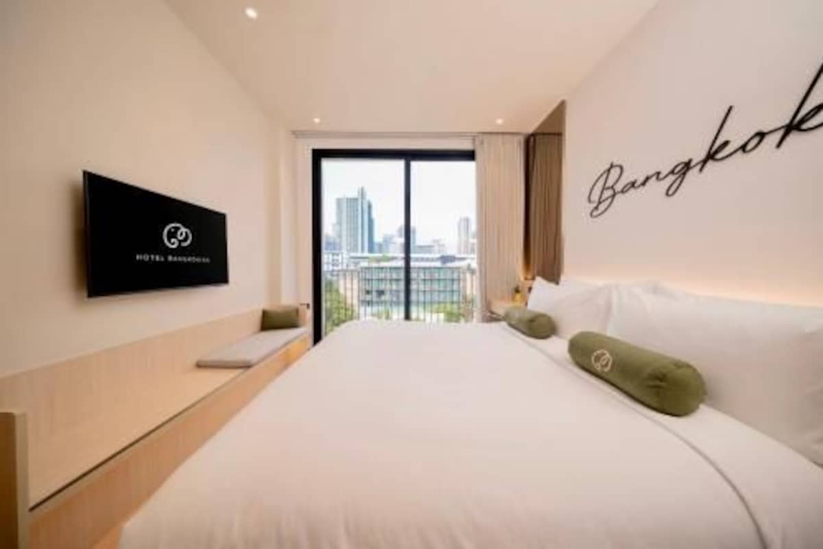 Habitación de hotel con cama, televisor en la pared y vista a la ciudad.