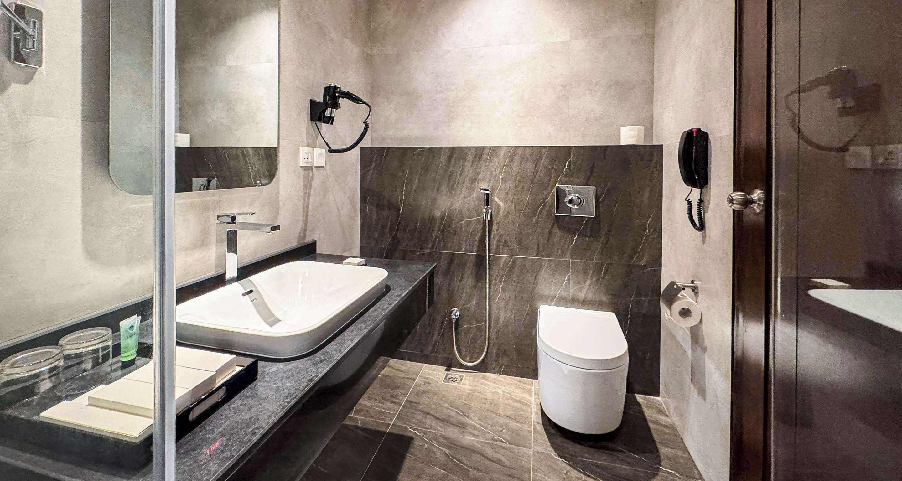 A modern bathroom with a large sink, a toilet, and a shower.