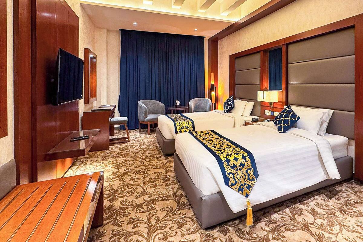 A hotel room with a large bed, two armchairs, a desk, and a television.