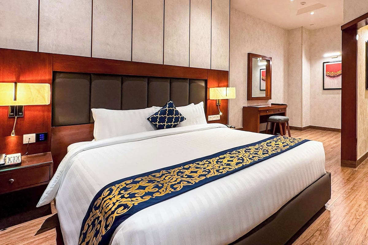 A hotel room with a large bed, bedside lamps, a desk, and a chair.
