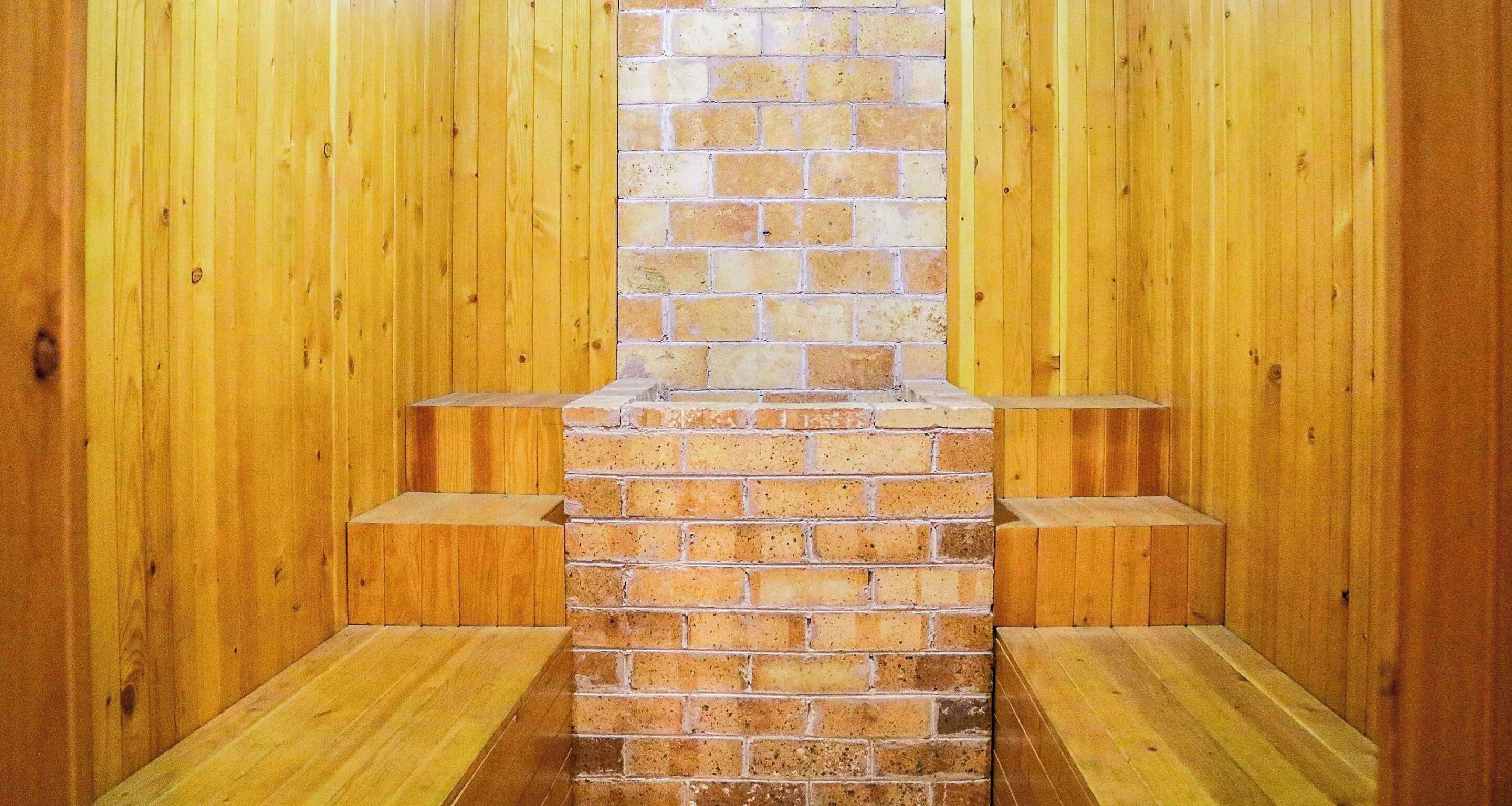 A sauna with a brick wall and wooden benches.