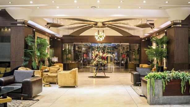 Un lobby moderno con un arreglo floral central, zonas de estar y un techo de diseño único.
