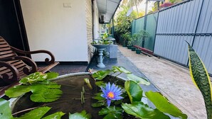 Ein Korridor mit Wasserelementen, darunter eine Lotusblume und eine Fontäne, der zu einem Schild für 'Aurelle Villa' führt.