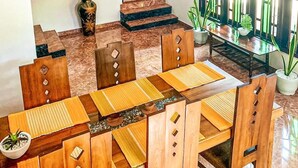 Ein Essbereich mit einem Holztisch und Stühlen, einer Vase mit Trockenpflanzen und einer Treppe zu einer Tür.