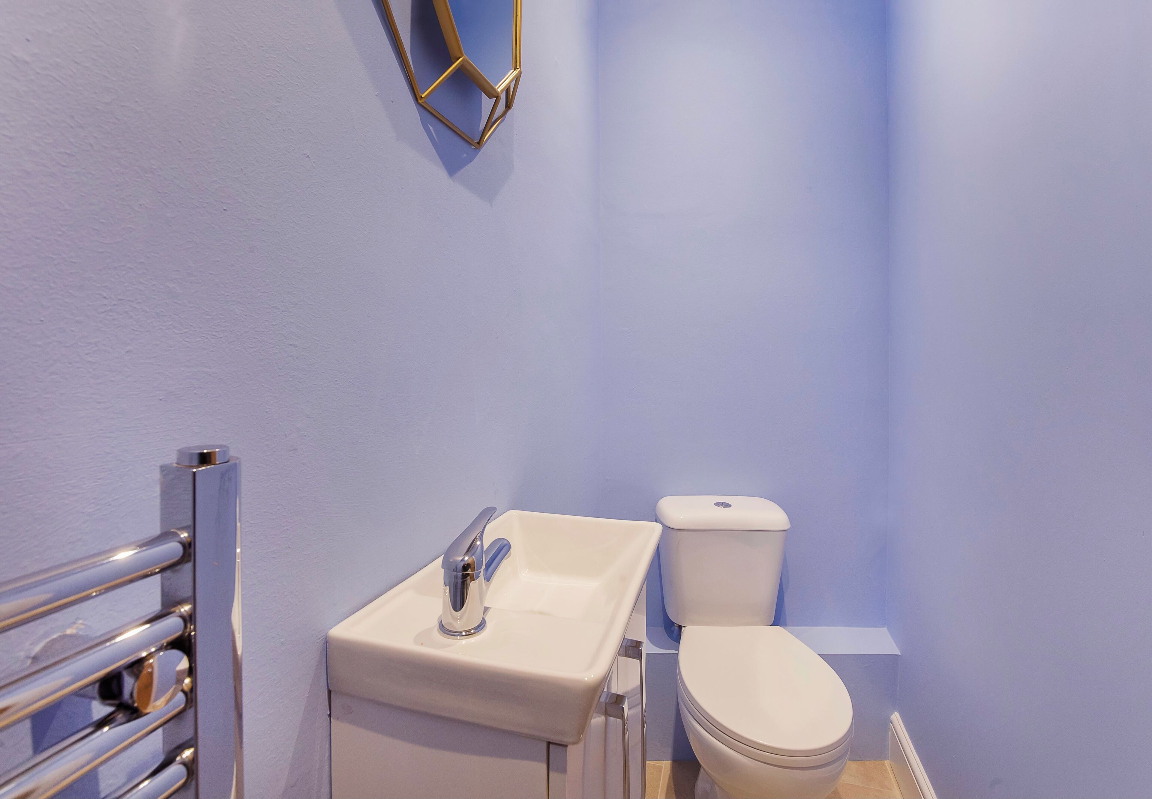 A bathroom with a white sink, a toilet, and a chrome towel rack.