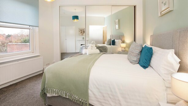 Un dormitorio con una cama grande, una ventana y un espejo.
