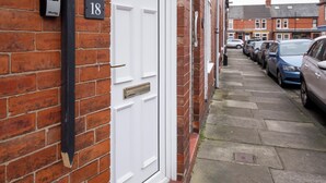 Una casa de ladrillo con una puerta blanca, un buzón y una placa con número.