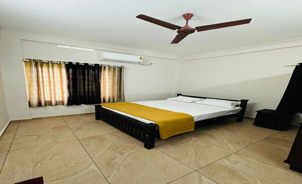 A bedroom with a bed, a ceiling fan, an air conditioning unit, and a window with curtains. - Malabar Apartments (Kanayannur)