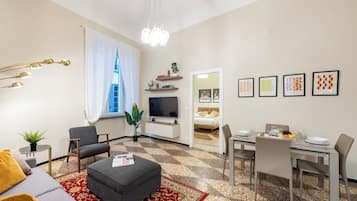 A modern living room with a sofa, ottoman, and a dining area with a table set for two.