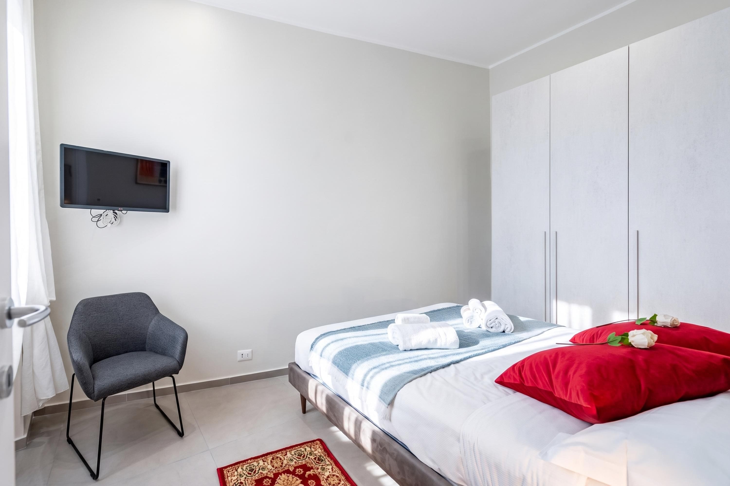 Ein Schlafzimmer mit einem Bett, einem Sessel, einem Fernseher und einem Kleiderschrank.