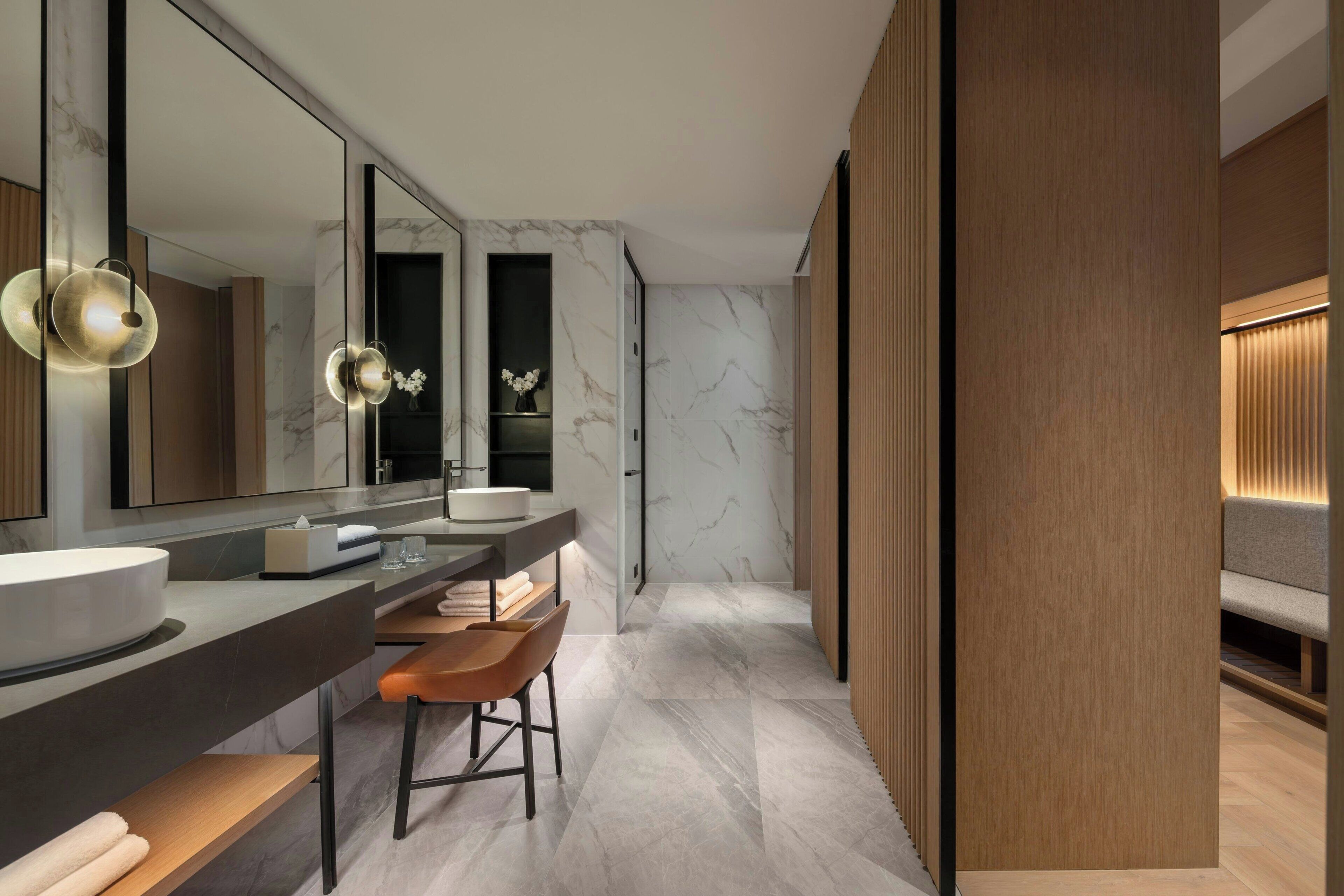 A modern bathroom with a large mirror, a round sink, and a bench.