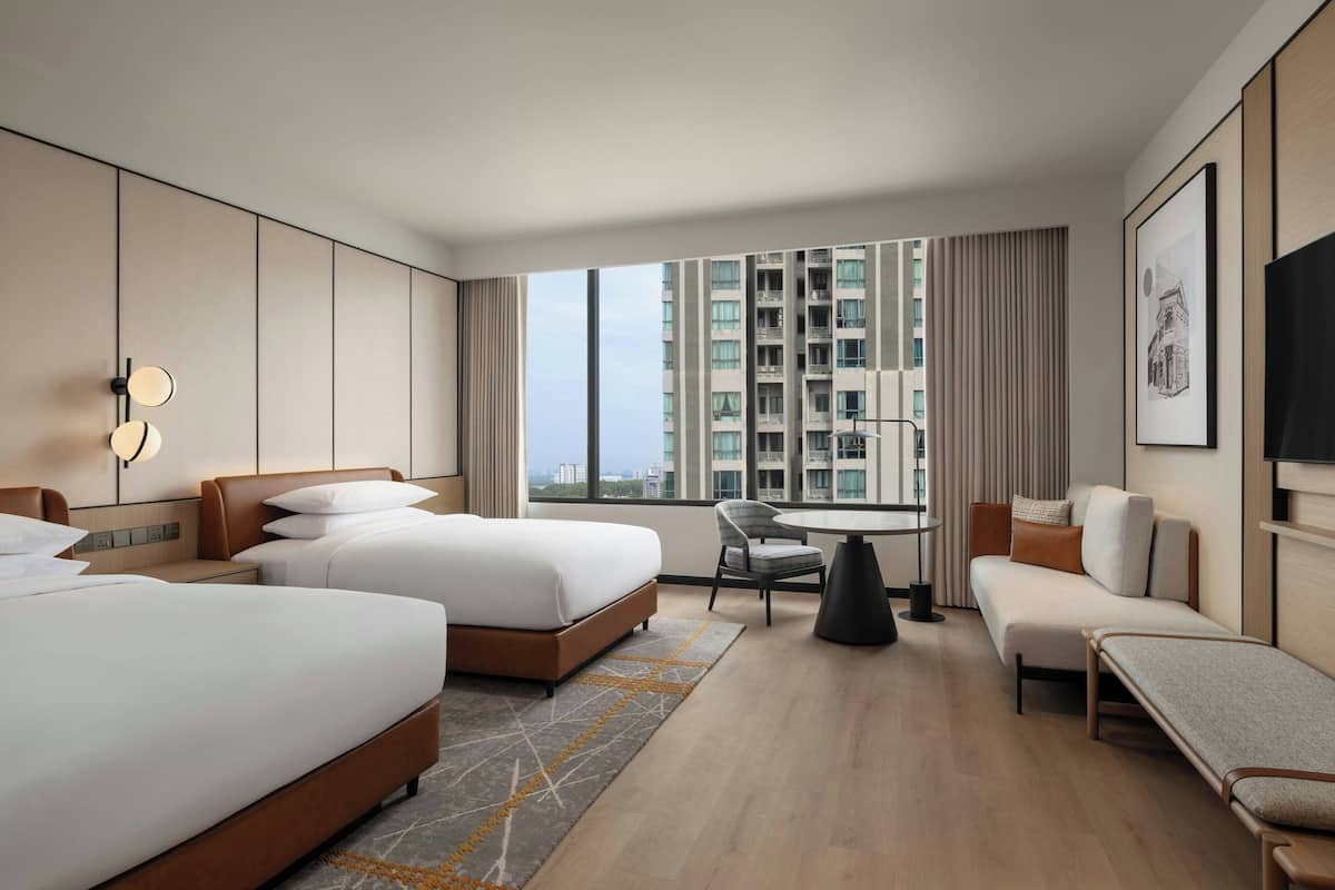 Une chambre d’hôtel moderne avec deux lits, un bureau et un canapé.