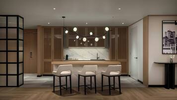 A modern kitchen with a marble countertop, wooden cabinets, and pendant lighting. There are three bar stools and a small table with a vase of flowers.