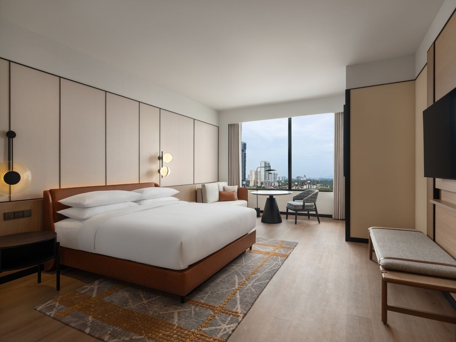 A modern hotel room with a large bed, a desk, a chair, and a TV.