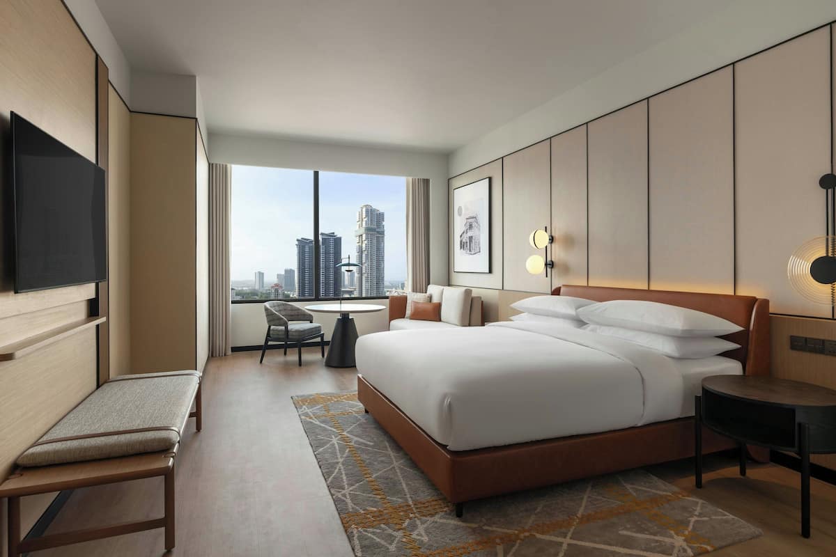 Une chambre d’hôtel moderne dotée d’un grand lit, d’un bureau, d’une chaise, d’une télévision et offrant une vue sur la ville.