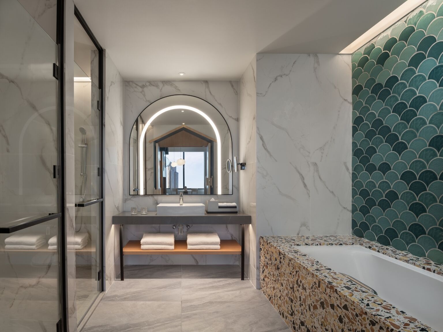 A modern bathroom with a glass-enclosed shower, a vanity with a large mirror, and a freestanding bathtub.