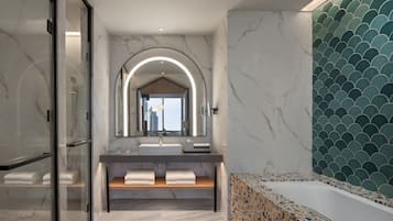 A modern bathroom with a glass-enclosed shower, a vanity with a large mirror, and a freestanding bathtub.