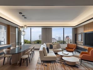 A modern living room with a dining area, large windows, and a city view.