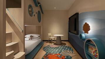 A modern hotel room with a bunk bed, a small round table, a TV mounted on the wall, and a decorative shelf with a shell.
