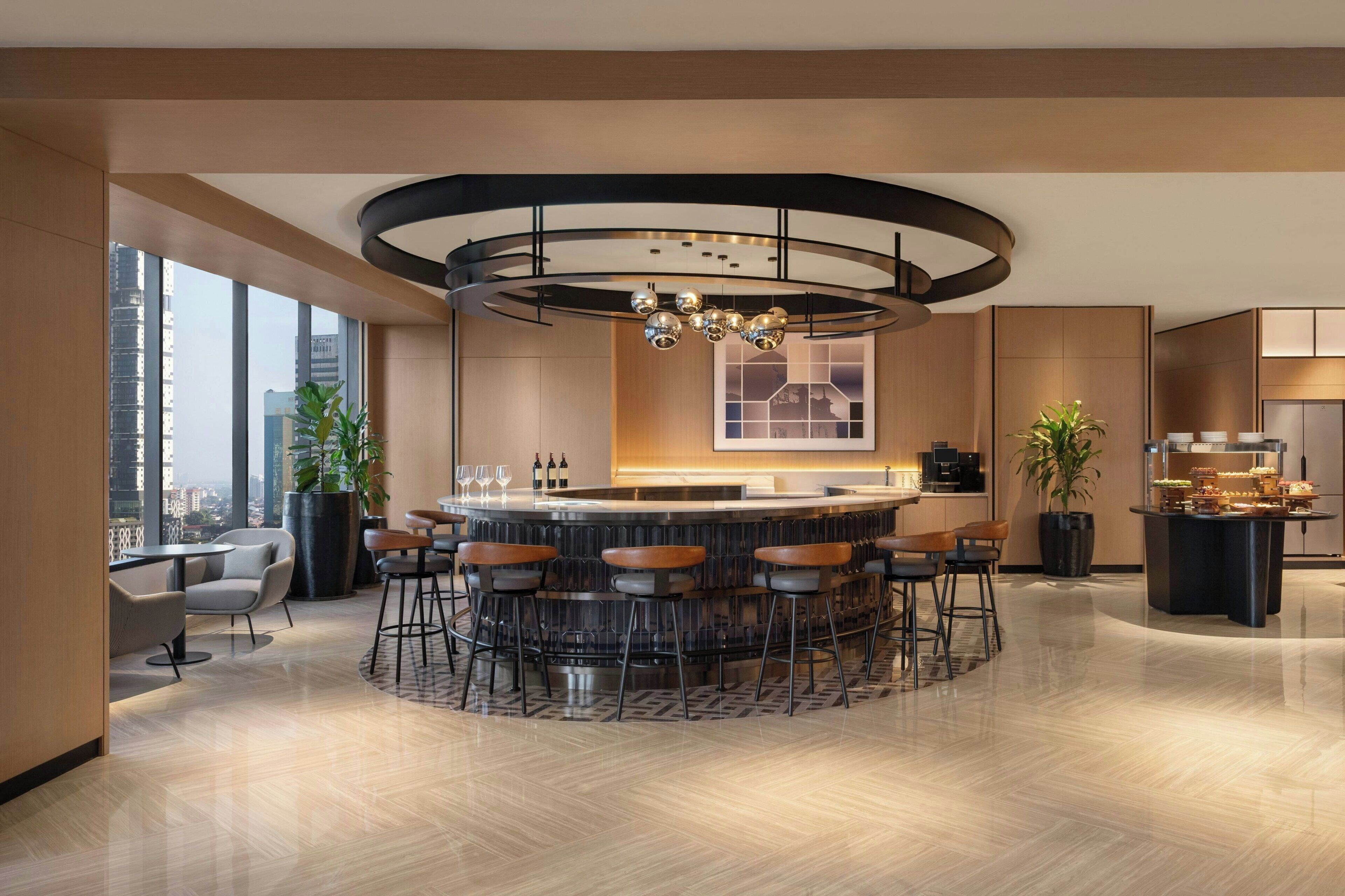 A modern bar area with a circular bar, multiple stools, and a central light fixture.