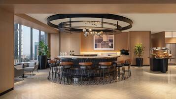 A modern bar area with a circular bar, multiple stools, and a central light fixture.
