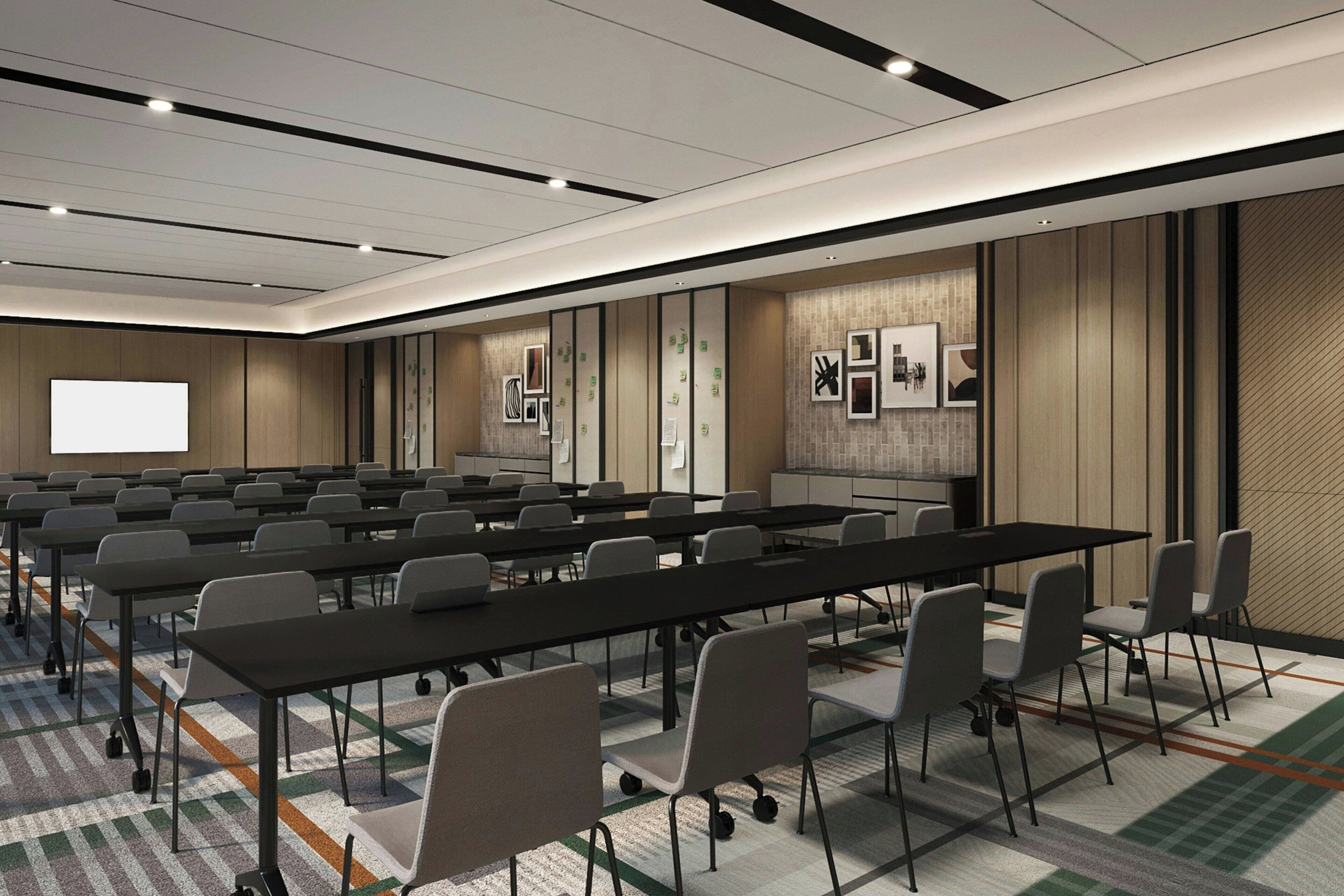 A conference room with multiple tables and chairs, a projector screen, and framed artwork on the walls.