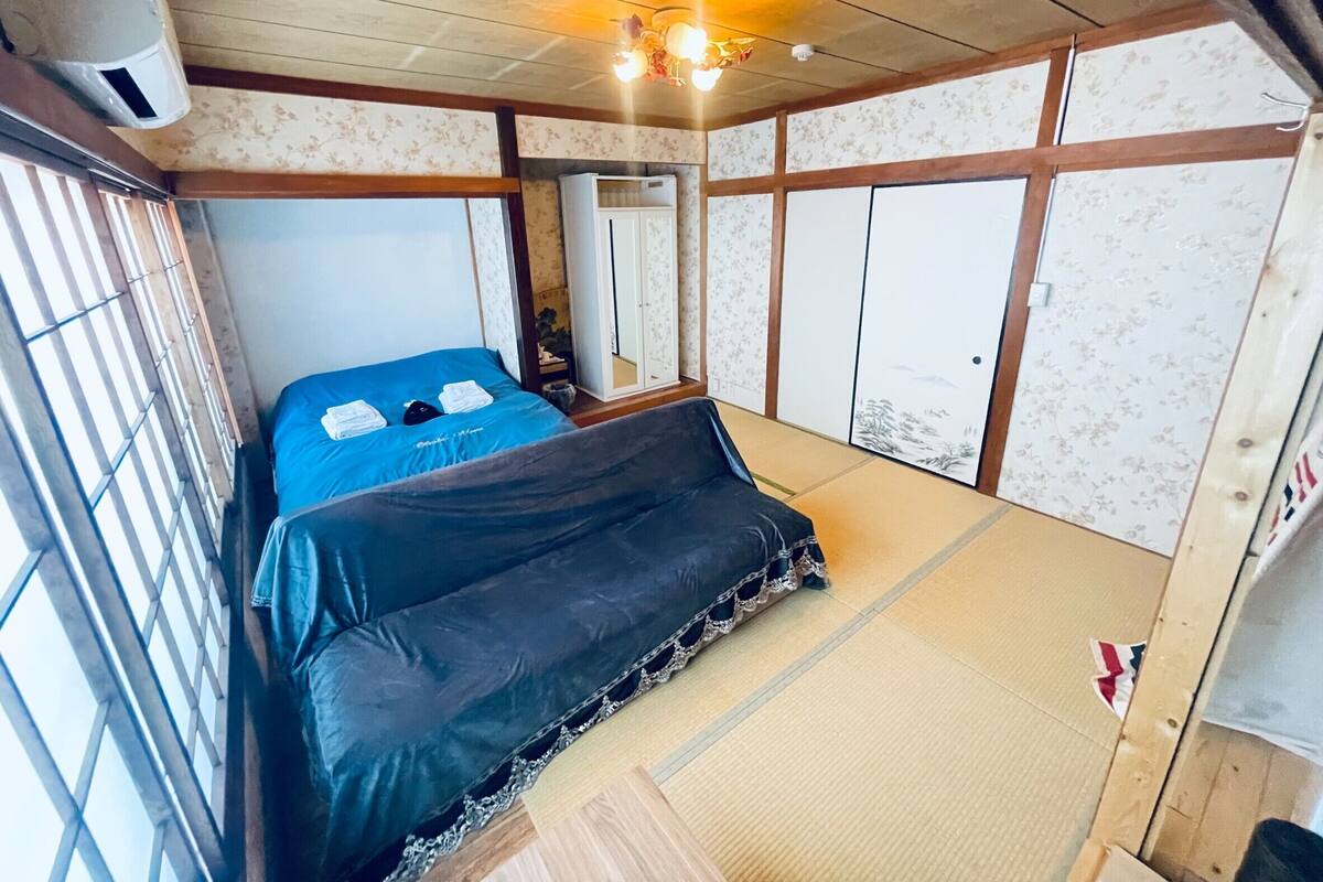 A room with a bed, a wardrobe, a mirror, and a ceiling fan.