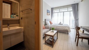 Une chambre d’hôtel moderne comprenant une salle de bain, un lit, un canapé, une petite table et une chaise.