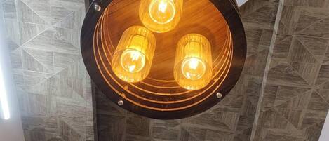 A circular ceiling light fixture with three bulbs, set in a wooden panel with a geometric pattern.
