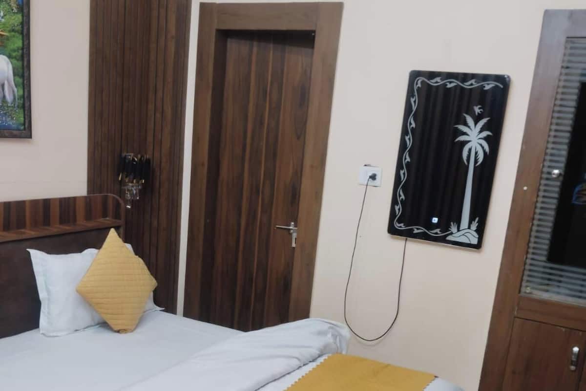 Ein Hotelzimmer mit einem Bett, einer Holztür, einer Wandklimaanlage und einem gerahmten Bild.