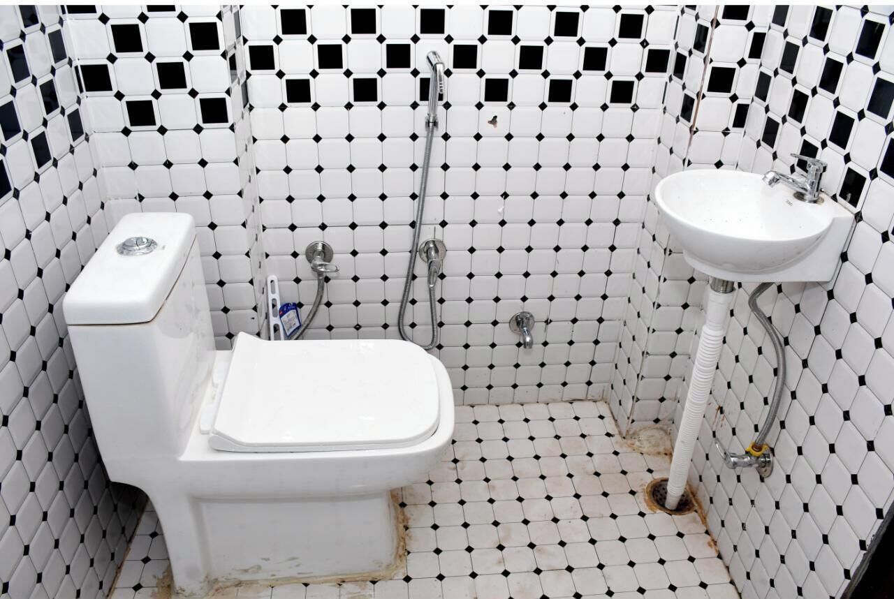 Baño con inodoro blanco, lavamanos y ducha. Las paredes están cubiertas de un diseño en blanco y negro.