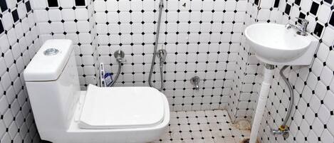 Baño con inodoro blanco, lavamanos y ducha. Las paredes están cubiertas de un diseño en blanco y negro.