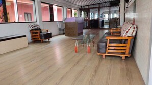 A spacious lobby with a wooden floor, seating area with sofas and chairs, a reception desk, and large windows allowing natural light. - AG Residency (Port Blair)