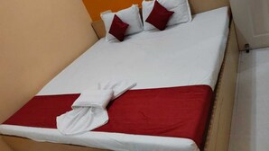 A bed with white linens, red bedding, and two red pillows. - AG Residency (Port Blair)