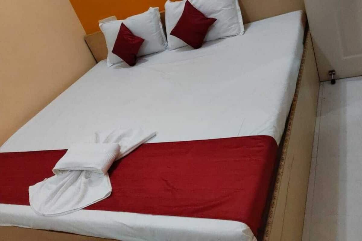 A bed with white linens, red bedding, and two red pillows.