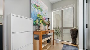 Een modern interieur met een houten bureau, een groot schilderij en een plant in pot.