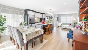 Een moderne keuken met een centraal eiland, een eethoek met een tafel en stoelen, en een woonkamer met een bank en televisie.
