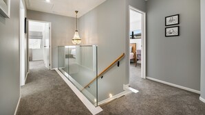 Een moderne hal met een glazen leuning, een houten handrailing en een kroonluchter.
