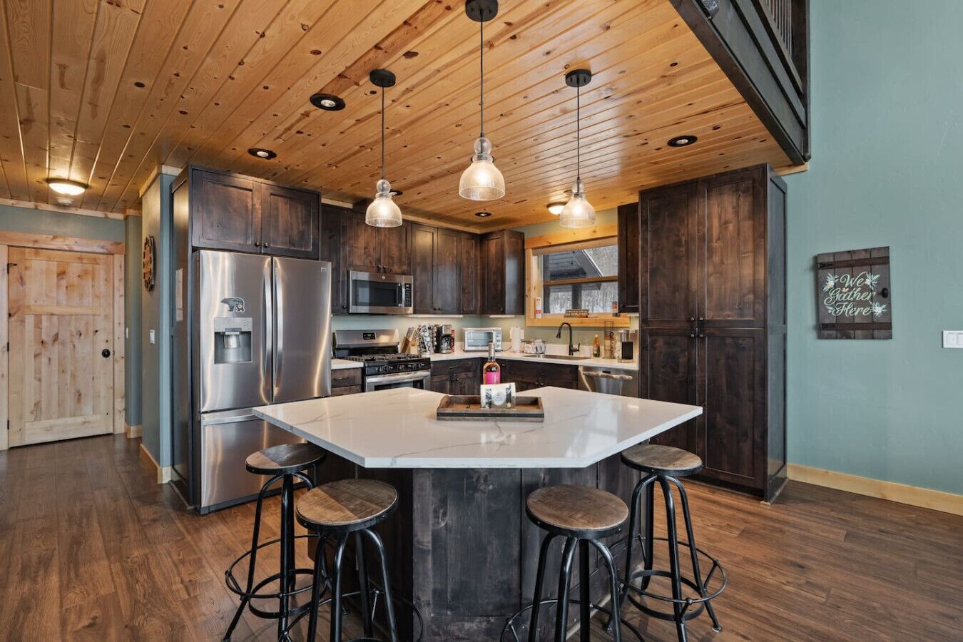 A modern kitchen with a large island, stainless steel appliances, and dark wood cabinets.