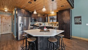 A modern kitchen with a large island, stainless steel appliances, and dark wood cabinets. - Alaskan Moose Lodge | Yellowstone + Hot Tub, Fire Pit & AC (Island Park)