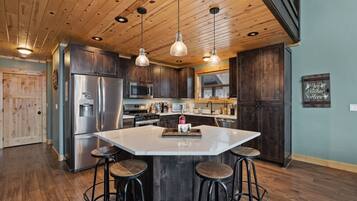 A modern kitchen with a large island, stainless steel appliances, and dark wood cabinets.