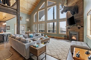 Un salón amplio con un sofá modular grande, una chimenea y una cabeza de ciervo montada.