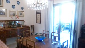 Un coin repas avec une table en bois, des chaises, un lustre et une vue à travers une porte vitrée.