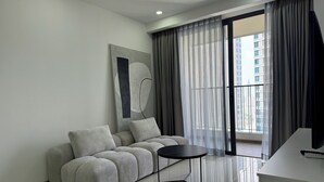 Un salón moderno con un sofá gris, una mesita negra y un ventanal con cortinas grises.